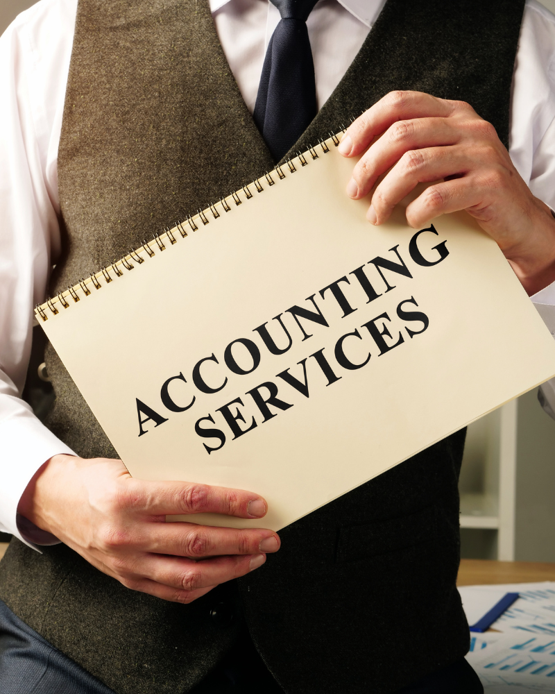 Accounting professional holding a notepad labeled "Accounting Services," representing organized accounting records and document management.